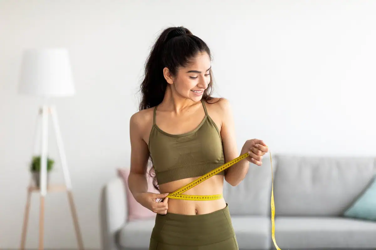 Woman measuring waist at home, highlighting Ozempic weight loss results